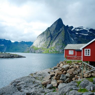 red and white wooden house in front of body of water