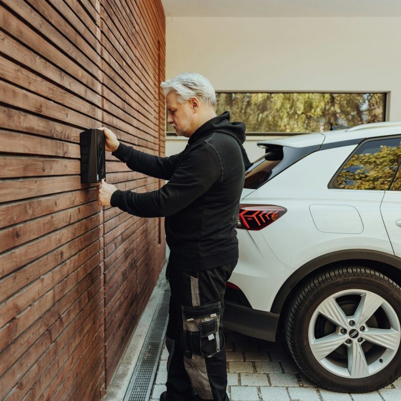 a man in a black jacket and black pants standing next to a white car