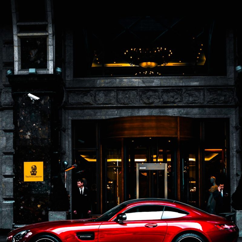 red coupe parked in front of black and gray building during daytime
