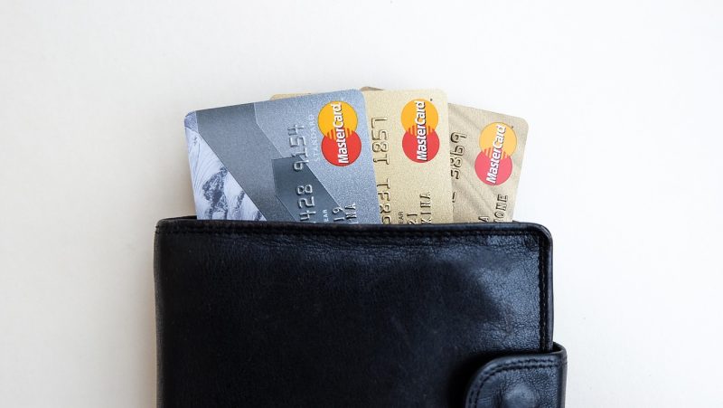 Iemand houdt een bankpas bij een betaalterminal voor contactloos betalen