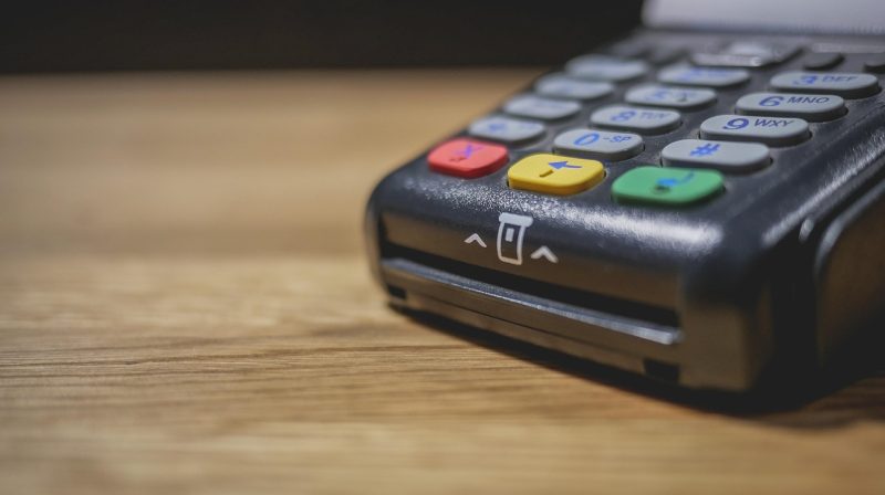 Persoon betaalt contactloos met smartphone bij een betaalterminal in een winkel