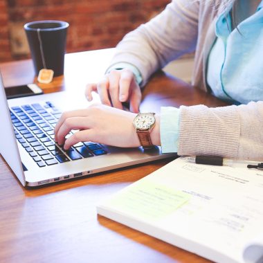 Student die aan een bureau zit en zijn studieschuld en beleggingen vergelijkt op een laptop