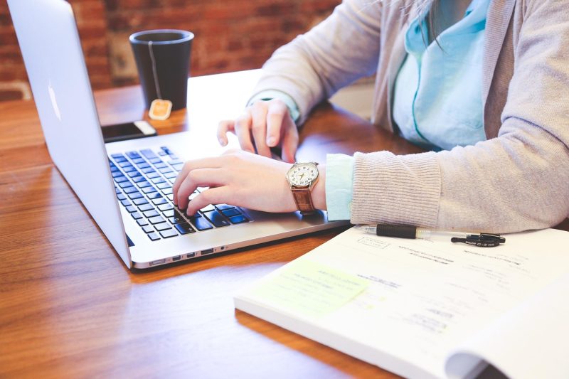 Student die aan een bureau zit en zijn studieschuld en beleggingen vergelijkt op een laptop