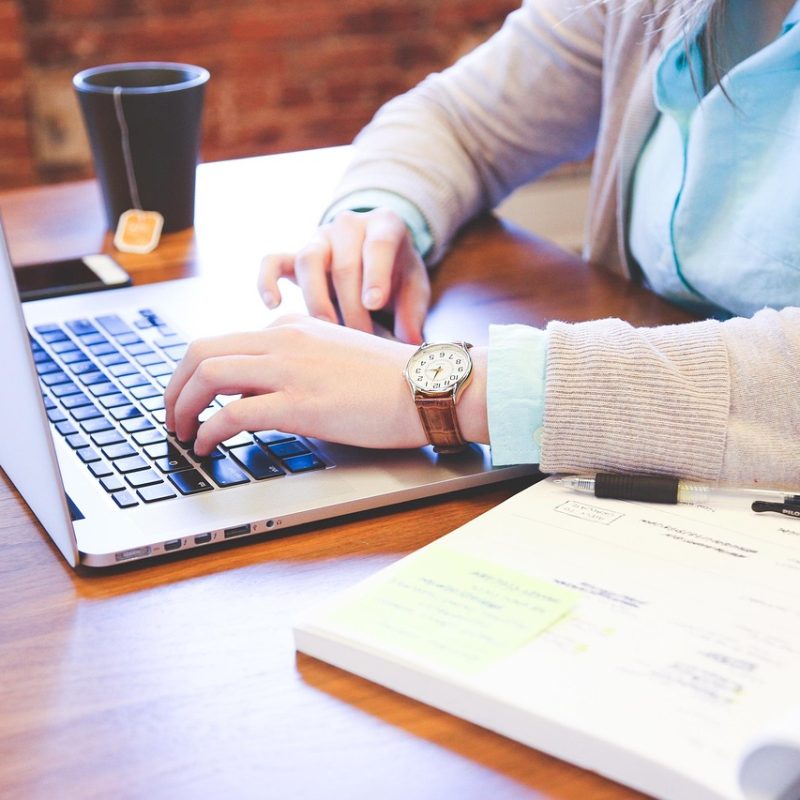 Student die aan een bureau zit en zijn studieschuld en beleggingen vergelijkt op een laptop