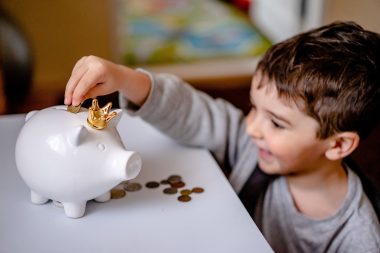 Ouder en kind zetten geld in een spaarpot als symbool voor beleggen voor je kind